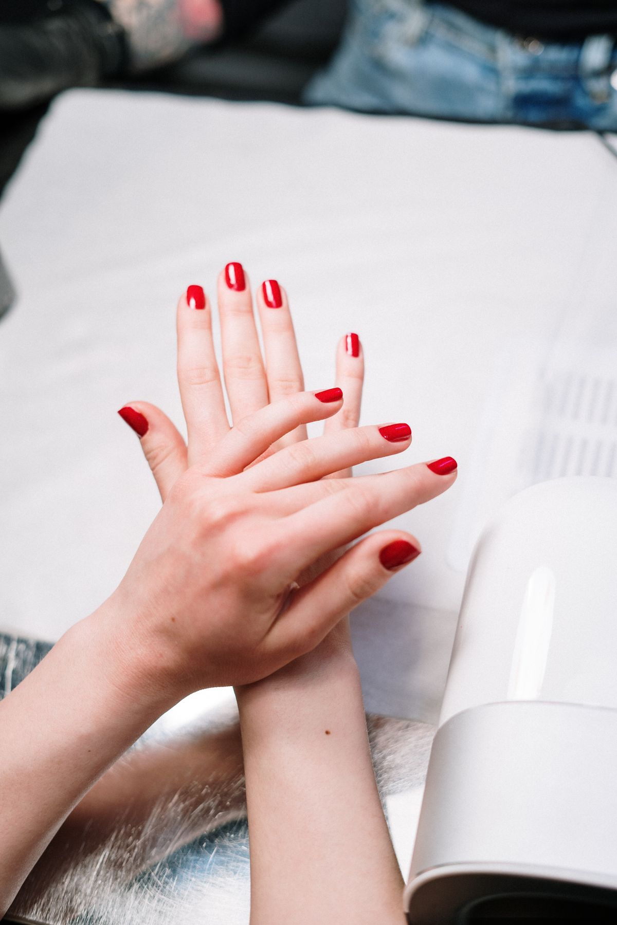 Red gel manicure set near a UV lamp, representing gel services at Pretty Lit Nail Bar